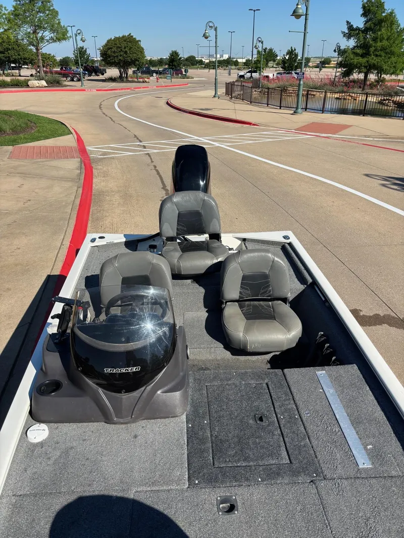 Slide: The Image of 2023 Tracker Pro 170 boat with seating, parked on a paved area under clear skies. - 6