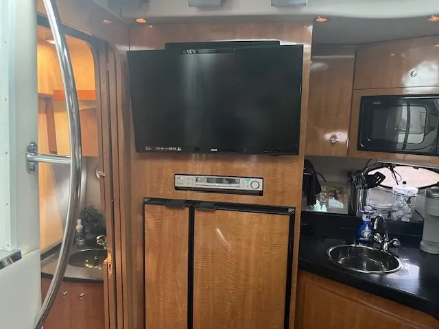 Slide: The Image of Interior of a 2003 Regal 3860 yacht with TV, kitchenette, and wood cabinetry. - 16