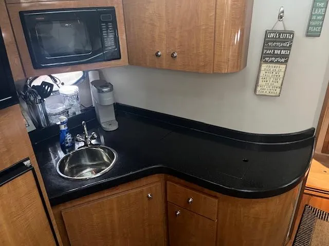 Slide: The Image of 2003 Regal 3860 yacht kitchen with microwave, sink, and wooden cabinetry. - 25