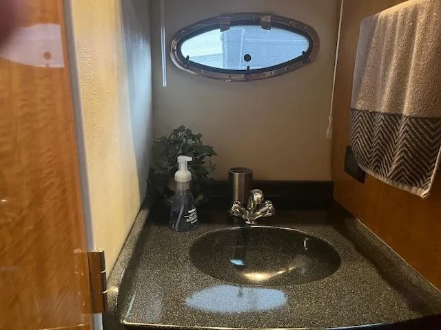 Slide: The Image of Compact bathroom in a 2003 Regal 3860 yacht with sink, towel, and porthole. - 32