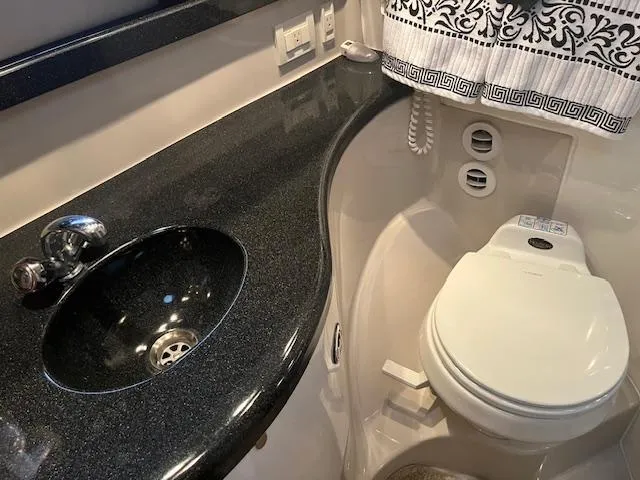 Slide: The Image of 2003 Regal 3860 yacht bathroom with black countertop and white toilet. - 34
