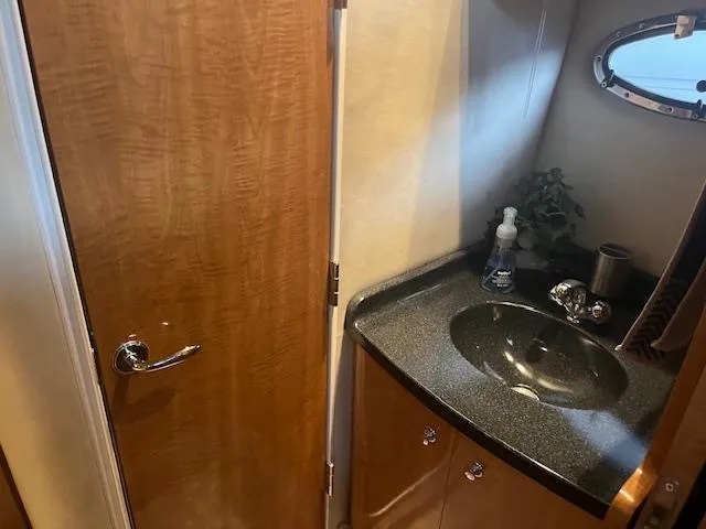 Slide: The Image of Compact bathroom in 2003 Regal 3860 yacht with wooden door and black countertop sink. - 38