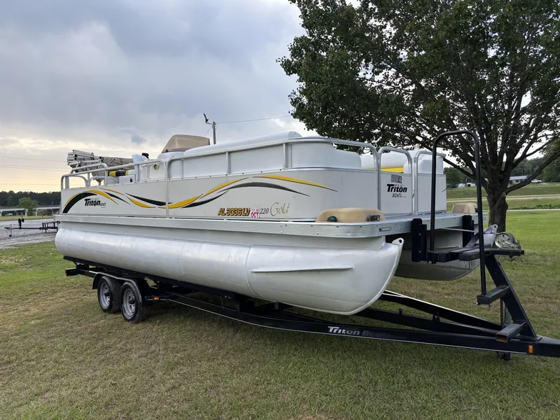 Slide: The Image of 2007 Triton 220 Gold pontoon boat on trailer, parked on grass near a tree. - 3