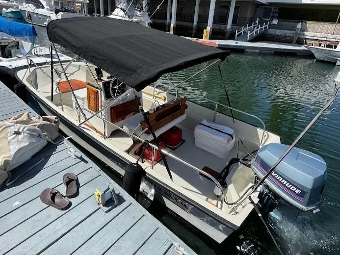Slide: The Image of 1983 Boston Whaler 17 Montauk boat docked with canopy and Evinrude outboard motor. - 10