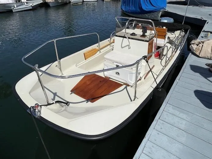 Slide: The Image of 1983 Boston Whaler 17 Montauk boat docked in marina, featuring classic design and open deck. - 3