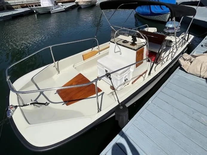 Slide: The Image of 1983 Boston Whaler 17 Montauk boat docked, featuring a canopy and open deck design. - 9