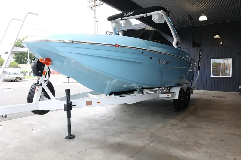 Slide: The Image of 2022 Tigé 25ZX boat in light blue on a trailer, parked indoors. - 4