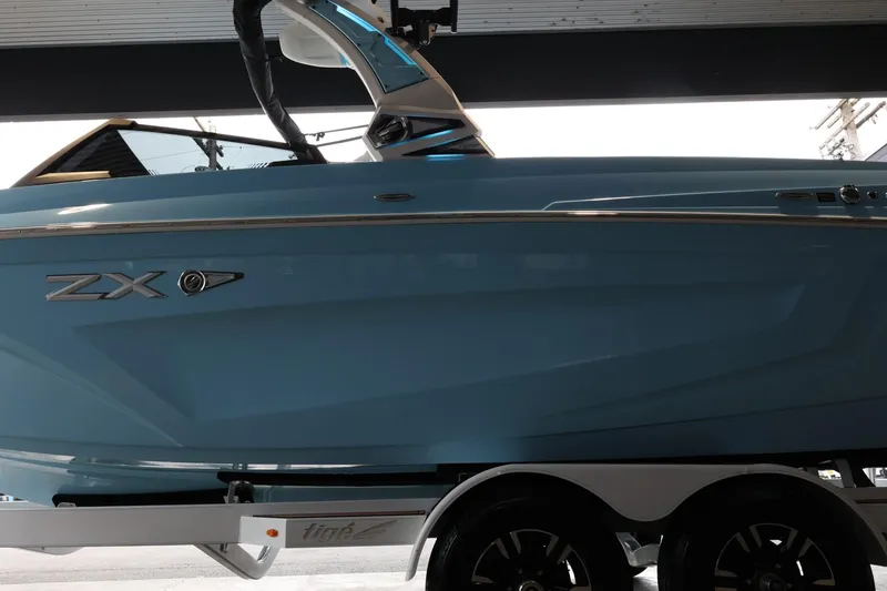 Slide: The Image of 2022 Tigé 25ZX boat in blue on a trailer, side view. - 5