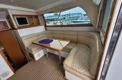 Slide: The Image of 2005 Cabo 35 Flybridge Sportfisher interior with beige seating and wooden table. - 14