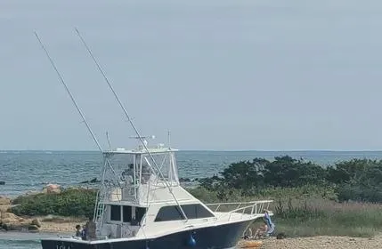 Slide: The Image of 2005 Cabo 35 Flybridge Sportfisher anchored near a rocky shoreline with ocean backdrop. - 6