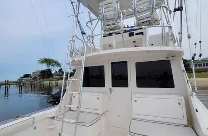 Slide: The Image of 2005 Cabo 35 Flybridge Sportfisher boat with ladder and seating, docked by the shore. - 9
