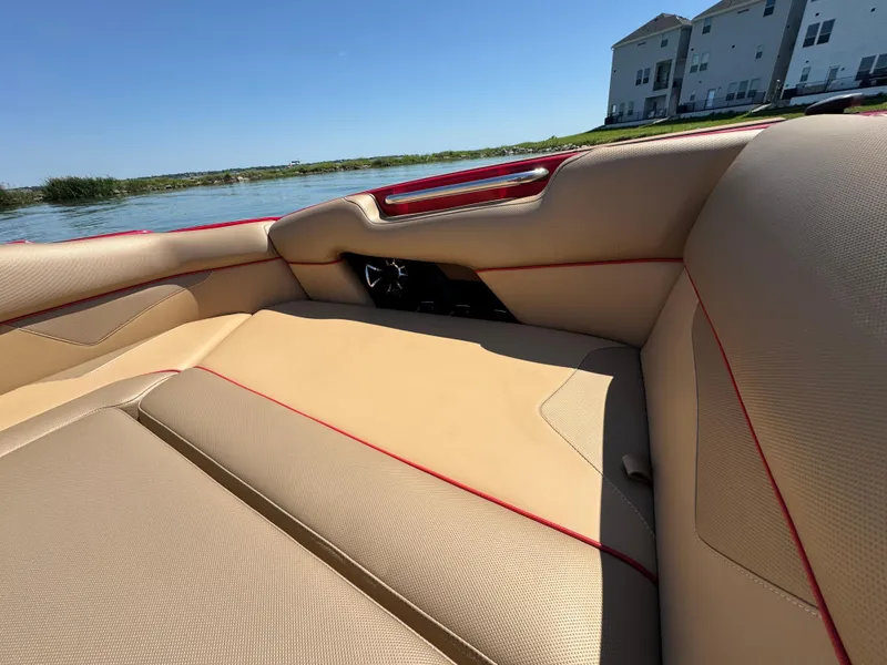 Slide: The Image of 2022 Moomba Makai boat interior with beige upholstery and red accents by the water. - 12