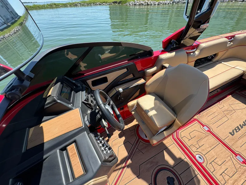 Slide: The Image of 2022 Moomba Makai boat interior with tan seats and modern dashboard on a sunny day. - 14
