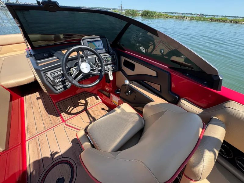 Slide: The Image of 2022 Moomba Makai boat interior with steering wheel, dashboard, and seating on a sunny day. - 15
