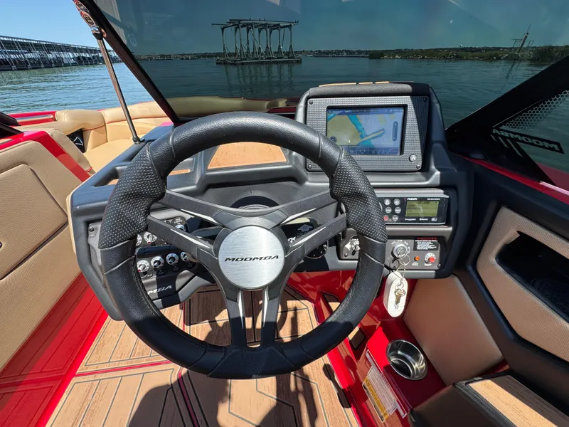 Slide: The Image of 2022 Moomba Makai boat dashboard with steering wheel and navigation screen, docked by the water. - 16