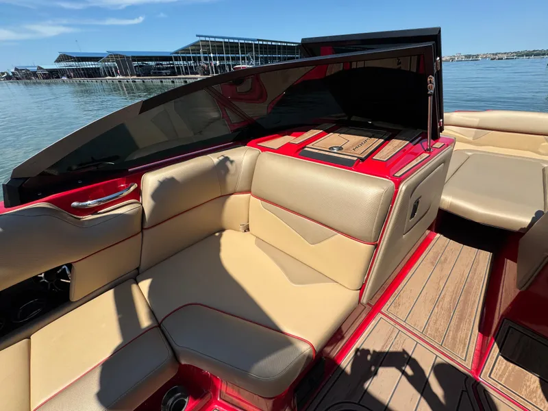 Slide: The Image of 2022 Moomba Makai boat interior with beige seating and red accents on a sunny day. - 17
