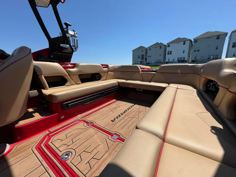 Slide: The Image of 2022 Moomba Makai boat interior with tan seating and red accents, under clear blue sky. - 19