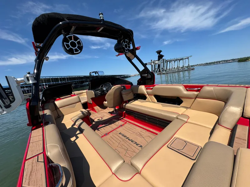 Slide: The Image of 2022 Moomba Makai boat interior with tan seating, red accents, and lake view. - 22