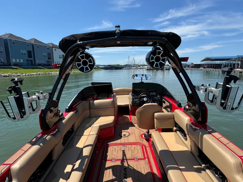 Slide: The Image of 2022 Moomba Makai boat interior with beige seating and black tower speakers on a sunny day. - 23