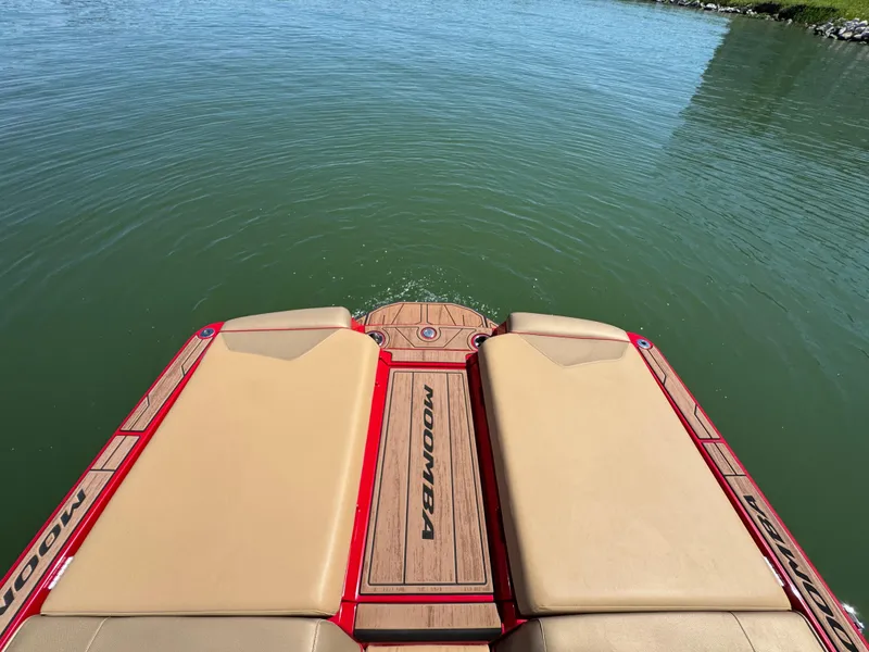 Slide: The Image of 2022 Moomba Makai boat stern with tan seats and red accents on calm water. - 24