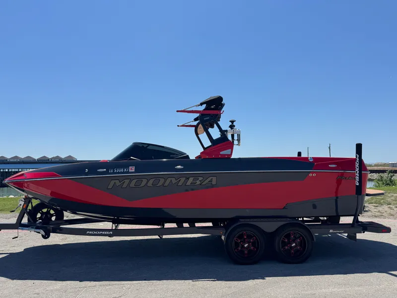 Slide: The Image of 2022 Moomba Makai boat in red and black on a trailer under clear blue sky. - 7