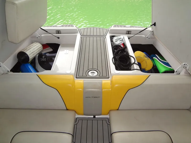 Slide: The Image of 2008 Correct Craft Super Air Nautique 230 boat storage compartments with gear, on a green water backdrop. - 37