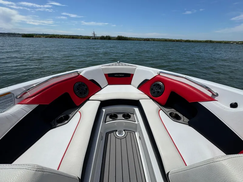 Slide: The Image of 2018 Nautique Super Air Nautique 210 boat interior with red and white seating on a lake. - 10