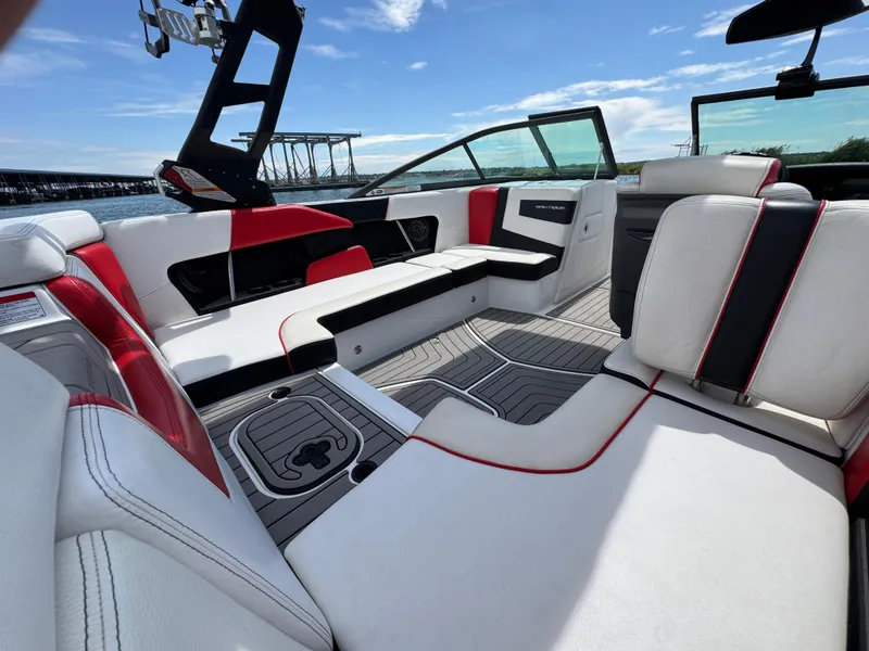 Slide: The Image of 2018 Nautique Super Air Nautique 210 interior with red and white seating, open water view. - 18