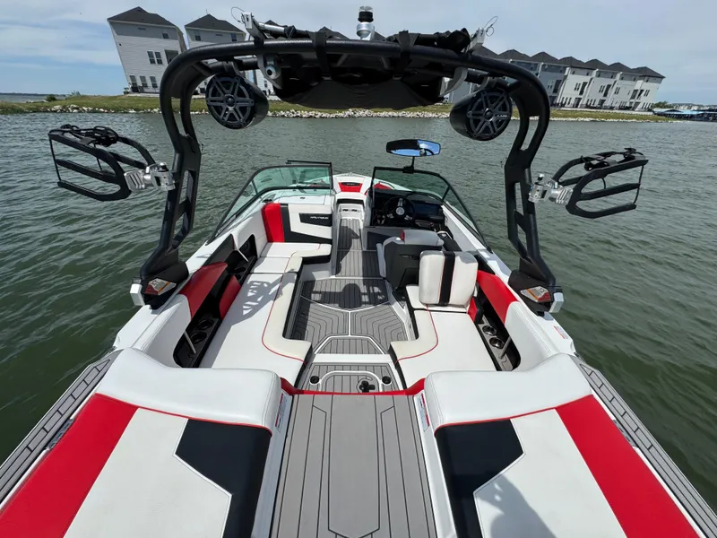 Slide: The Image of 2018 Nautique Super Air Nautique 210 boat interior with red accents on a lake. - 19