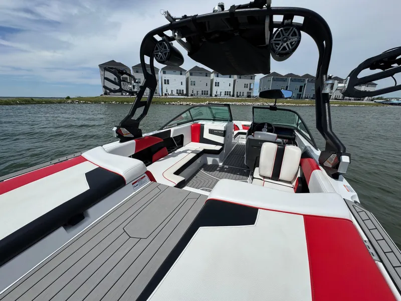Slide: The Image of 2018 Nautique Super Air Nautique 210 boat with red and white interior on a lake. - 21