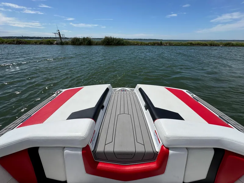 Slide: The Image of 2018 Nautique Super Air Nautique 210 boat on water, featuring red and white seating. - 22