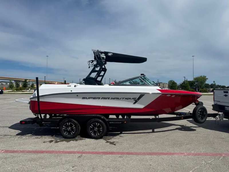 Slide: The Image of 2018 Nautique Super Air Nautique 210 boat on trailer, red and white design. - 8