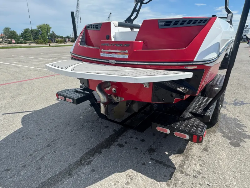 Slide: The Image of 2018 Nautique Super Air Nautique 210 boat rear view in parking lot. - 9