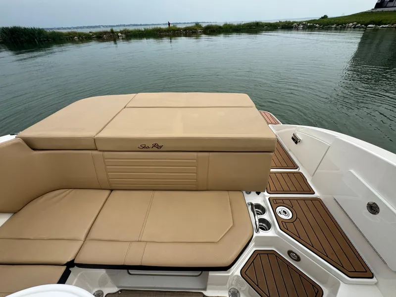 Slide: The Image of 2019 Sea Ray SPX 230 boat with tan seating and wooden deck by the water. - 16