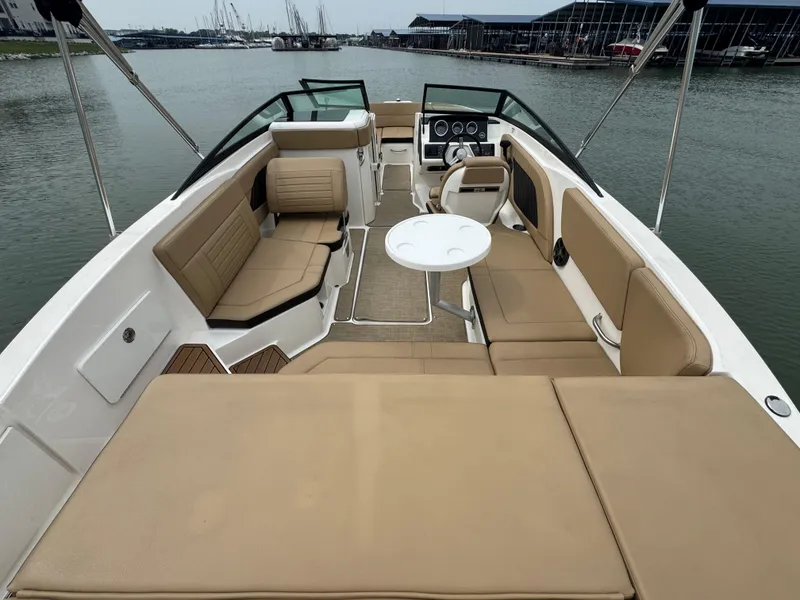 Slide: The Image of 2019 Sea Ray SPX 230 boat interior with beige seating and a round table on the water. - 18