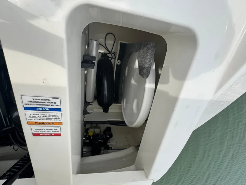 Slide: The Image of Storage compartment of a 2019 Sea Ray SPX 230 boat, showing equipment and safety labels. - 20