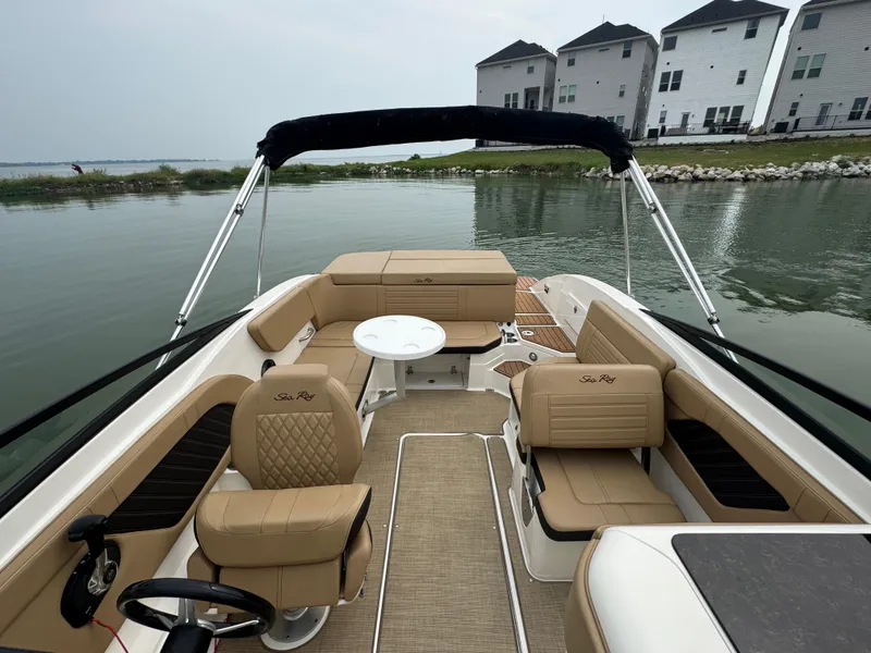 Slide: The Image of 2019 Sea Ray SPX 230 boat interior with tan seating, table, and waterfront view. - 9