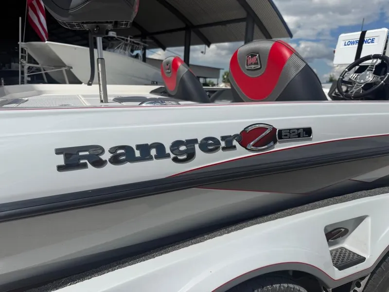 Slide: The Image of 2021 Ranger Z521L Intracoastal boat with red and black seating, docked under a canopy. - 9