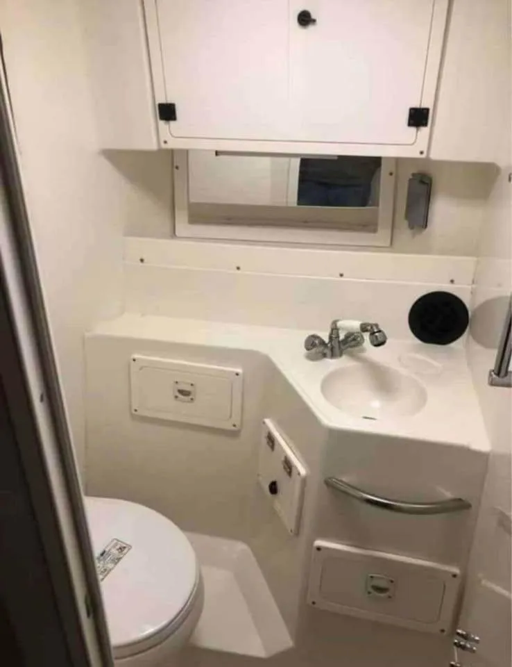 Slide: The Image of Compact bathroom in 1998 Hydra-Sports 3100 boat, featuring sink, toilet, and storage cabinets. - 5