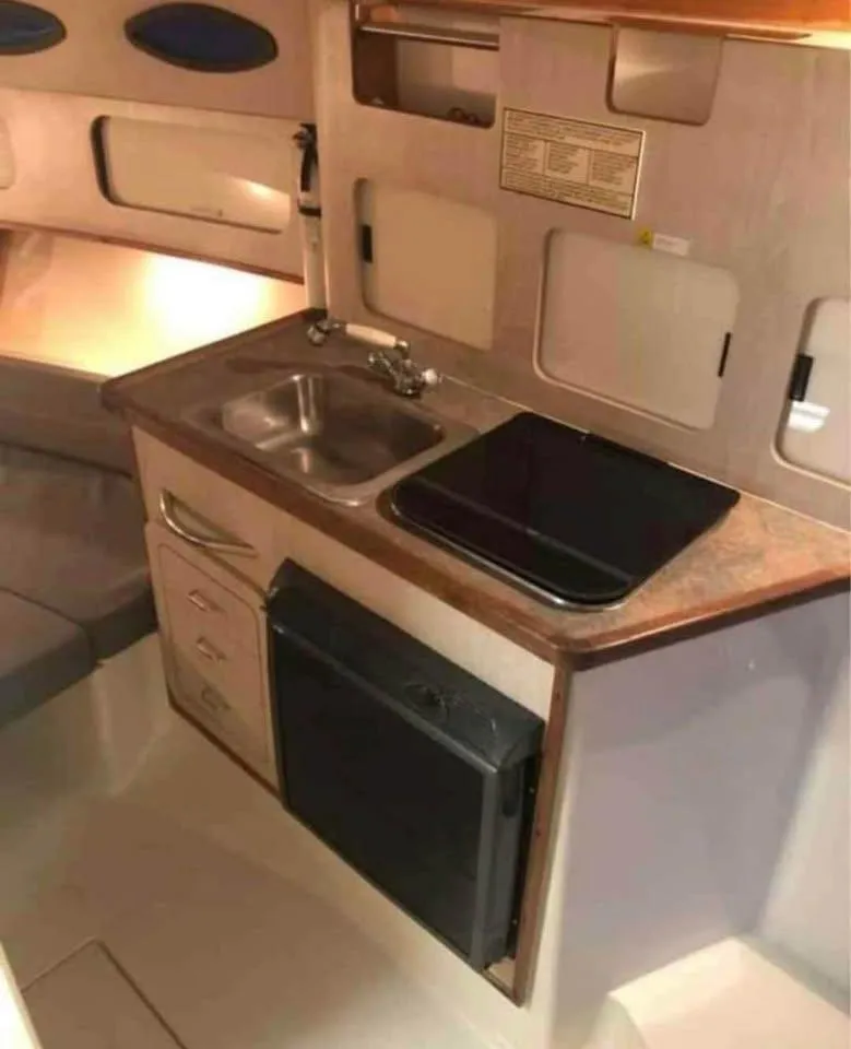 Slide: The Image of 1998 Hydra-Sports 3100 25th Anniversary boat interior with kitchenette, sink, and storage. - 4