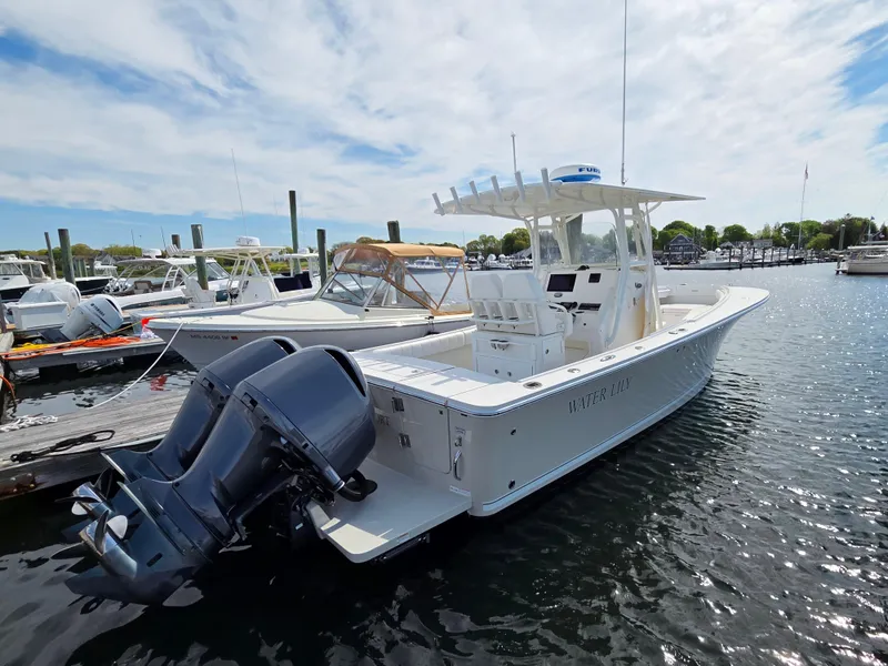 Slide: The Image of 2014 Regulator 28 Forward Seating boat docked in a marina under a partly cloudy sky. - 14