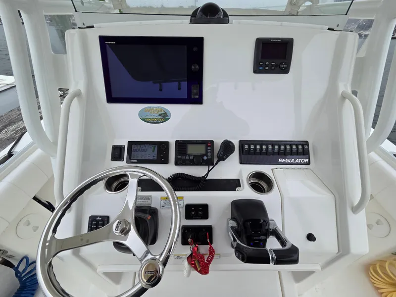 Slide: The Image of 2014 Regulator 28 Forward Seating boat dashboard with steering wheel and electronic controls. - 7
