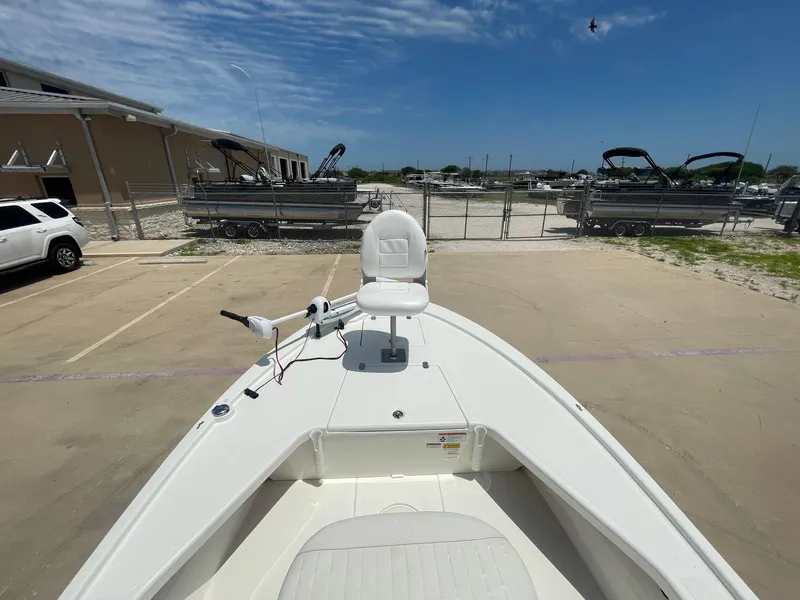 Slide: The Image of 2013 Mako 18lts boat parked in a lot, featuring a white deck and seating. - 12