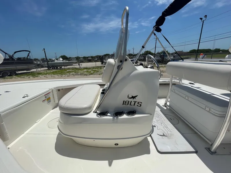 Slide: The Image of 2013 Mako 18LTS boat interior with seating and console, under clear blue sky. - 18