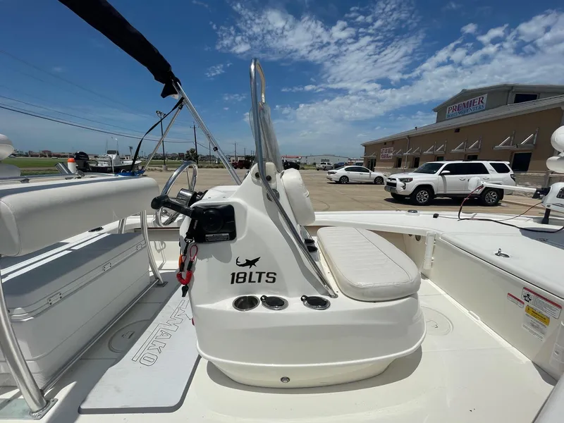 Slide: The Image of 2013 Mako 18LTS boat interior with seating and steering, parked outdoors under a blue sky. - 19