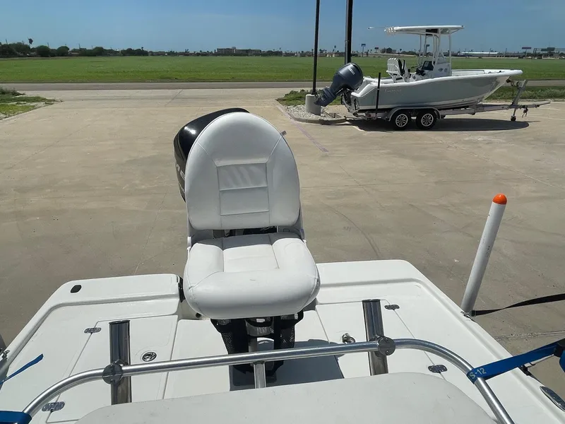 Slide: The Image of 2013 Mako 18lts boat with white seating, parked on concrete near another boat. - 30