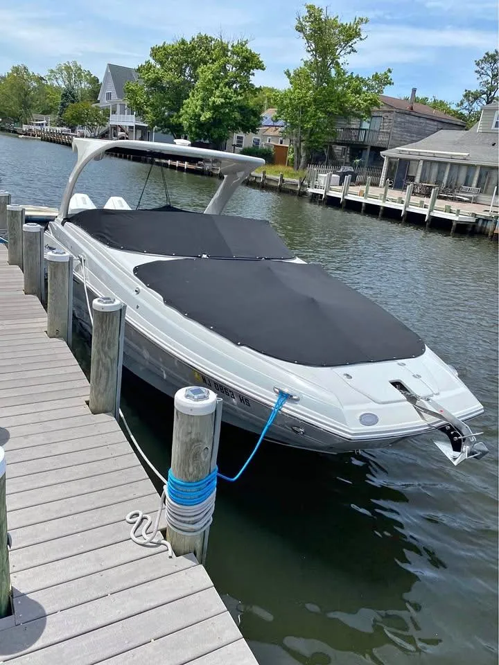Slide: The Image of 2022 Crownline Eclipse E305 XS boat docked on a calm waterfront. - 2
