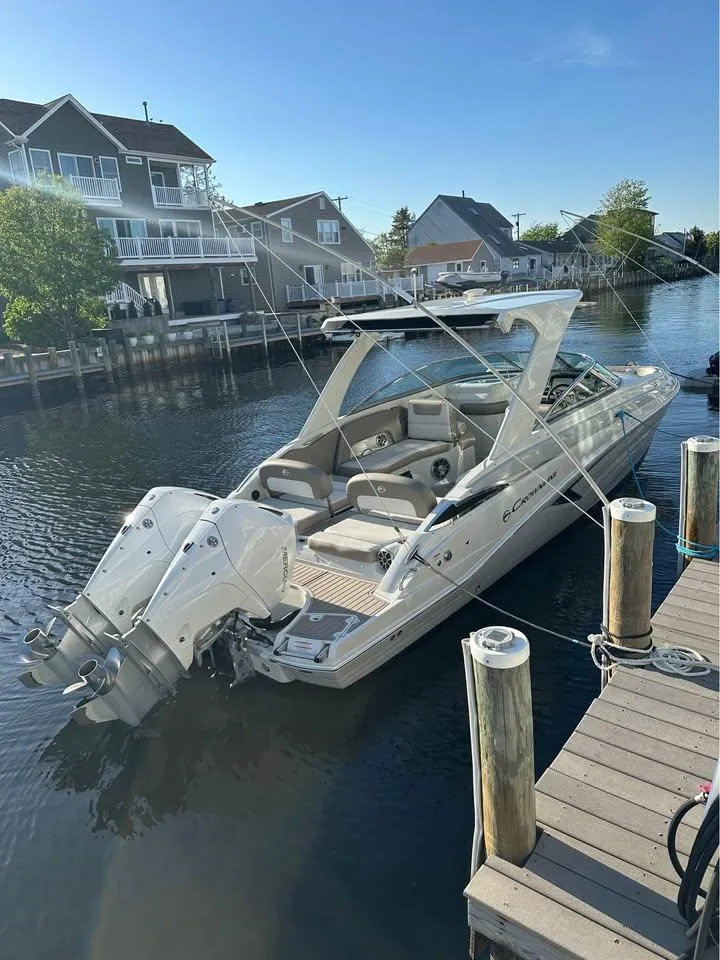 Slide: The Image of 2022 Crownline Eclipse E305 XS boat docked in a serene canal setting. - 4