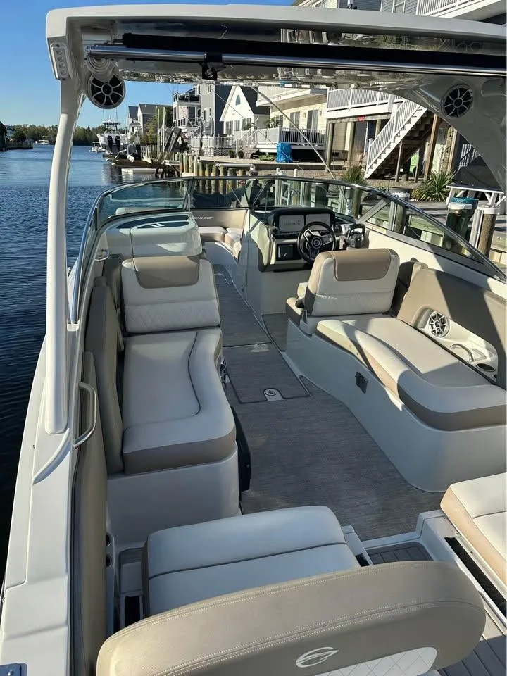 Slide: The Image of 2022 Crownline Eclipse E305 XS boat with spacious seating, docked by waterfront homes. - 5