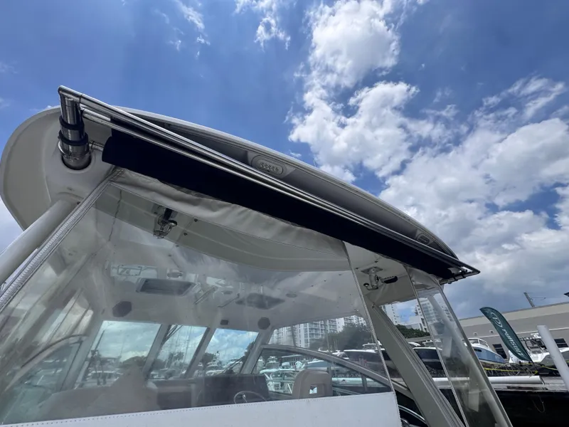 Slide: The Image of 2015 Boston Whaler 345 Conquest boat with clear canopy under a partly cloudy sky. - 29